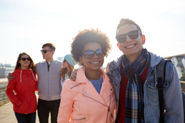 happy teenage friends in shades hugging on street