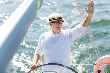senior man at helm on boat or yacht sailing in sea