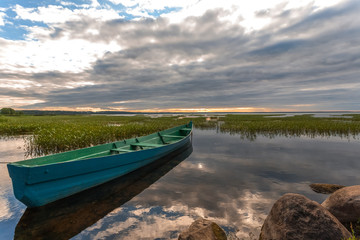 Obraz premium The fishing wooden boat at the coast before an evening storm.
