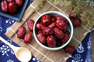 A bowl of red dates on spread a blue cloth on the desktop