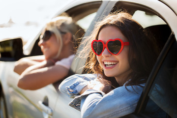 happy teenage girls or women in car at seaside