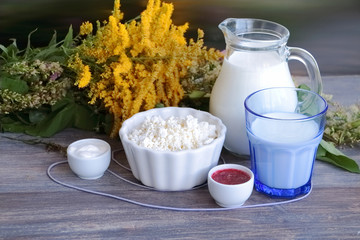 Concept of natural products and healthy eating - field flowers and organic dairy products on wooden table - summer rural symbol