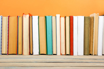 Books on grunge wooden table desk shelf in library. Back to school background with copy space for your ad text. Old hardback no labels, blank spine