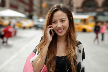 Young Asian woman in city talking on cell phone
