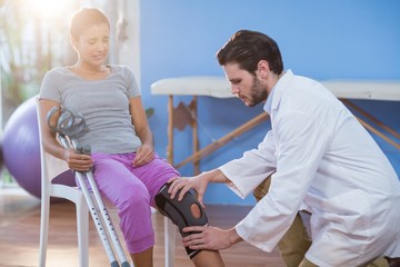 Physiotherapist examining female patients knee