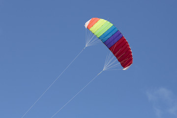 Multi-colored kite flying with a blue sky