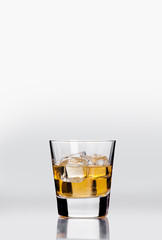 whiskey in a transparent glass with ice on a light background 