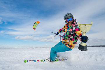 Sportsman is kiting with a cup in his arms on the background of snow and blue sky