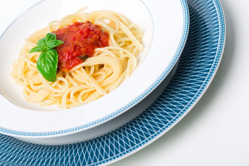 Original Italian Spaghetti with fresh tomato sauce and fresh basil. White wood table background.