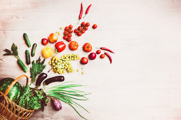 Fresh tomatoes, chili pepper and other spices and herbs around modern Turquoise plate in the center of wooden table and cloth napkin. Top view. Blank place for your text. Close-up.