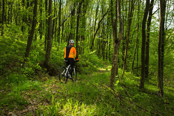 Naklejka premium Biker in orange jersey on the forest road