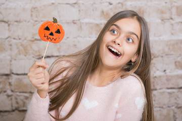 halloween candy. Cheerful girl with a sweet, beautiful teenager girl holding a candy on stick. Girl with long hair in a Halloween theme 
