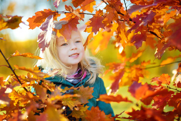 Naklejka na ściany i meble Cute little girl having fun on beautiful autumn day