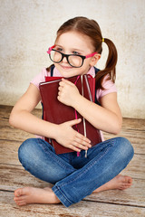 Smart and cute preschool girl with books and wearing glasses