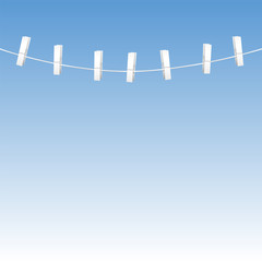 Clothes line rope with seven white clothes pins - blue sky background.