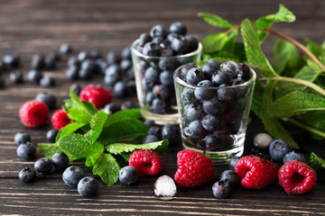 Blueberries, raspberries and mint at black wooden table.