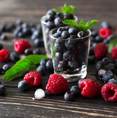 Blueberries, raspberries and mint at black wooden table.