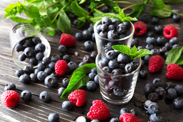 Blueberries, raspberries and mint at black wooden table.