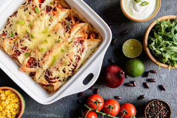 Traditional Mexican enchiladas with chicken meat, spicy tomato sauce, corn, beans and cheese