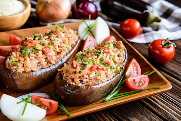 Baked stuffed eggplant with rice, tomato and onion on a wooden plate