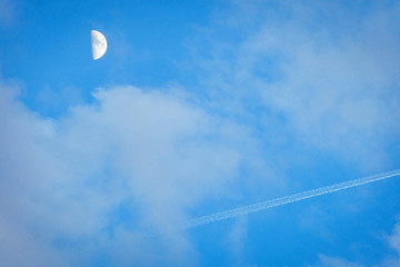 The moon and the trace of the plane in the blue sky