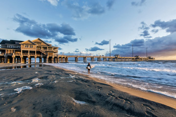 A surfer studying the waves just after sunise at Jeannette's Pier, Nags Head, N.C.