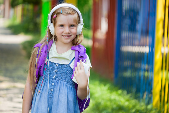 little girl goes to school and listen to music via smartphone