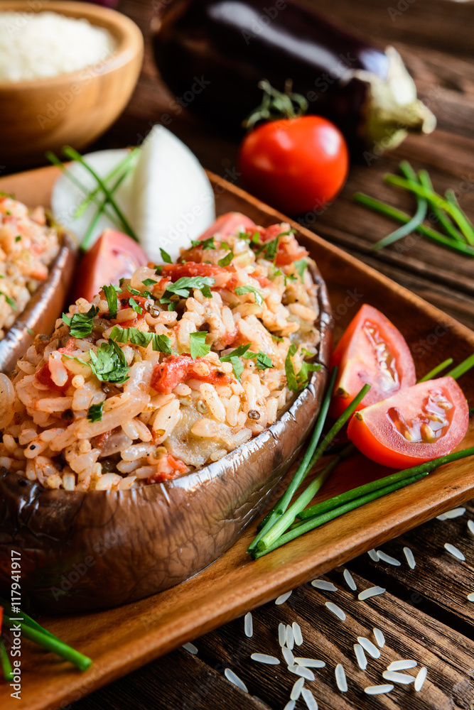 Wall mural Baked stuffed eggplant with rice, tomato and onion on a wooden plate - Wall murals