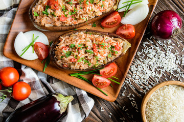 Baked stuffed eggplant with rice, tomato and onion on a wooden plate