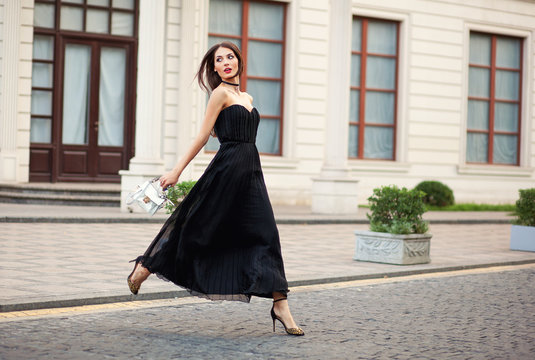 Eautiful Fashionable Young Woman In Long Dress Running With Bag.