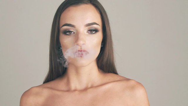Pretty girl blowing fume on background. Slow motion
