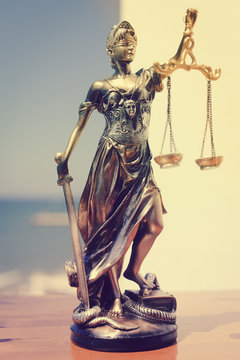 Justice Themis goddess sculpture on bright sky copy space background.