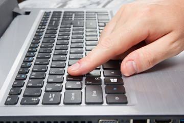 Man's hands typing laptop keyboard making online payment at home against the wooden table. On-line...