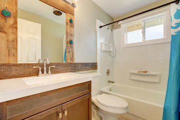 Interior of white bathroom with mirror in decorative wooden frame.