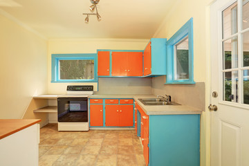 Old fashioned kitchen interior with orange and blue cabinets.