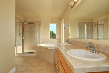 Spacious creamy bathroom with corner bathtub.