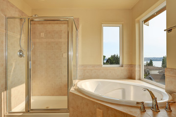 Spacious creamy bathroom with corner bathtub.