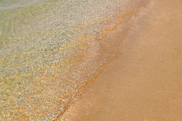 Fototapeta na wymiar Soft wave of transparent ocean water on sandy beach. Tourism Concept Background