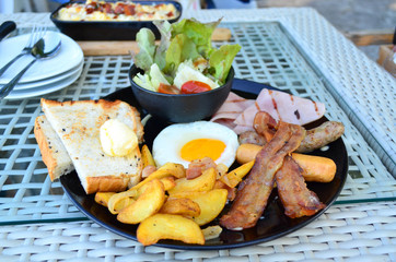 Traditional American breakfast - fried egg, bacon, ham, sausage,