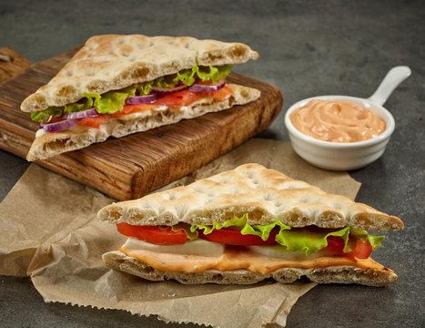 various sandwiches on paper and wooden cutting board