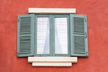 Decorative old window on an old red stucco wall 