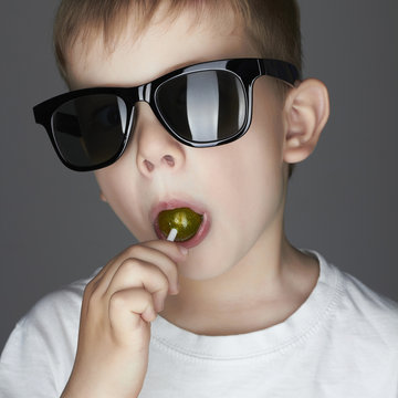 Funny Young Boy Eating A Lollipop.Fashionable child in sunglasses