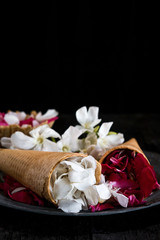 Pink and white flowers in ice cream cone on black background