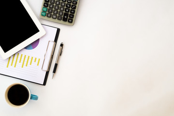 White office desk table with blank screen tablet, chart or graph over backboard , pen, calculator and cup of coffee.  Top view with copy space
