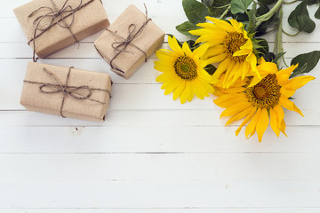 Background with a bouquet of sunflowers and gift boxes on a whit