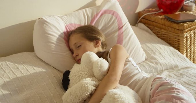 Adorable cute awaking girl in the bed with her toy