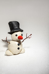 little snowman made of plasticine standing on real snow
