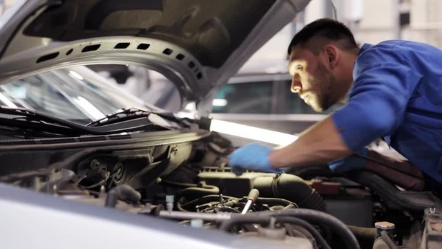 mechanic man with lamp repairing car at workshop 7
