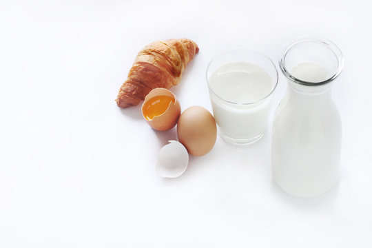 Glass of milk and a bottle of milk, eggs, bread, white background.