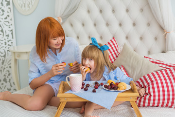 Mother looks at little daughter how she eats